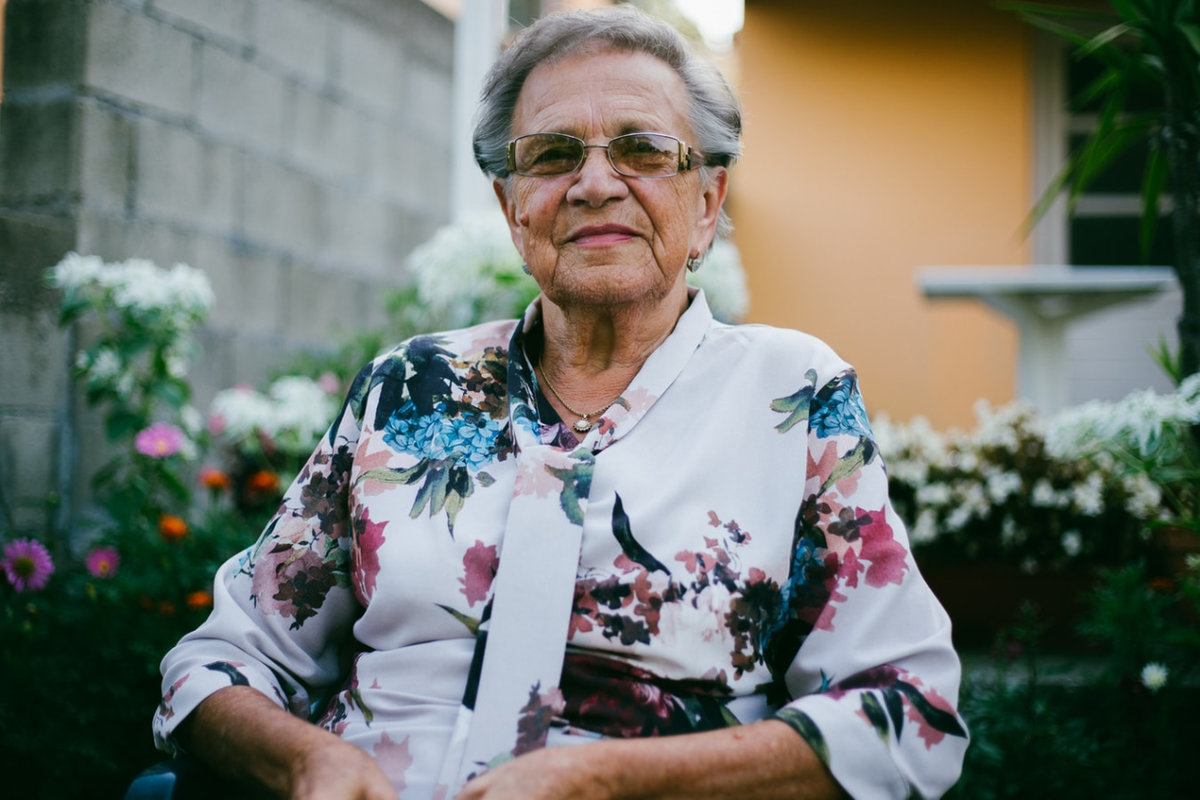 an elderly lady wearing a floral blouse and glasses